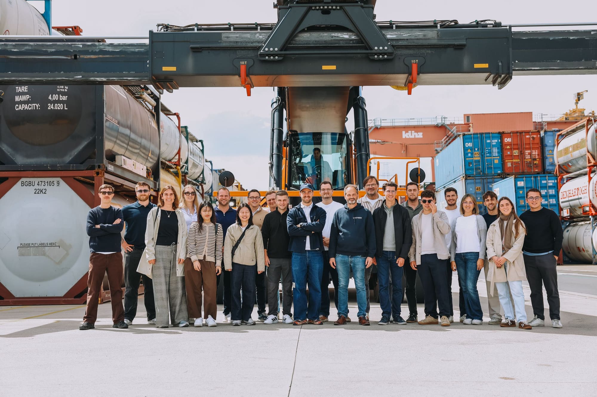 The Loxygen Academy group standing beneath a container crane at a chemical/tank terminal